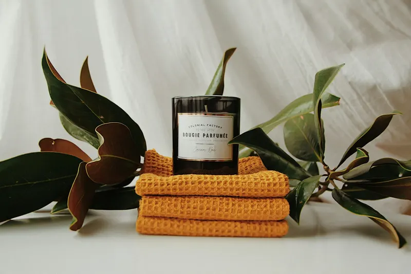 Candle on folded yellow towels with leaves