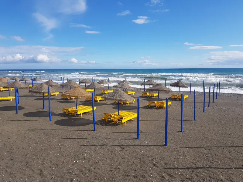 Yellow sunbeds and straw parasols on a sandy beach