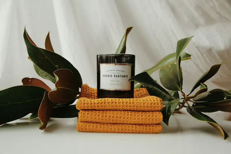 Bougie sur des serviettes jaunes pliées avec des feuilles